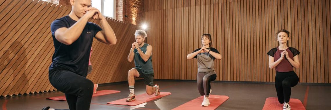 Adults practicing exercises on yoga mats in a contemporary studio setting.